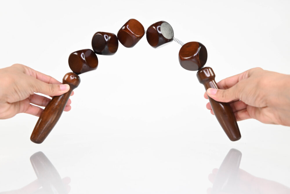 Flexible wooden massage rollers body roller with five dark brown cube-shaped rollers, showing how it bends to adapt to the body's contours.