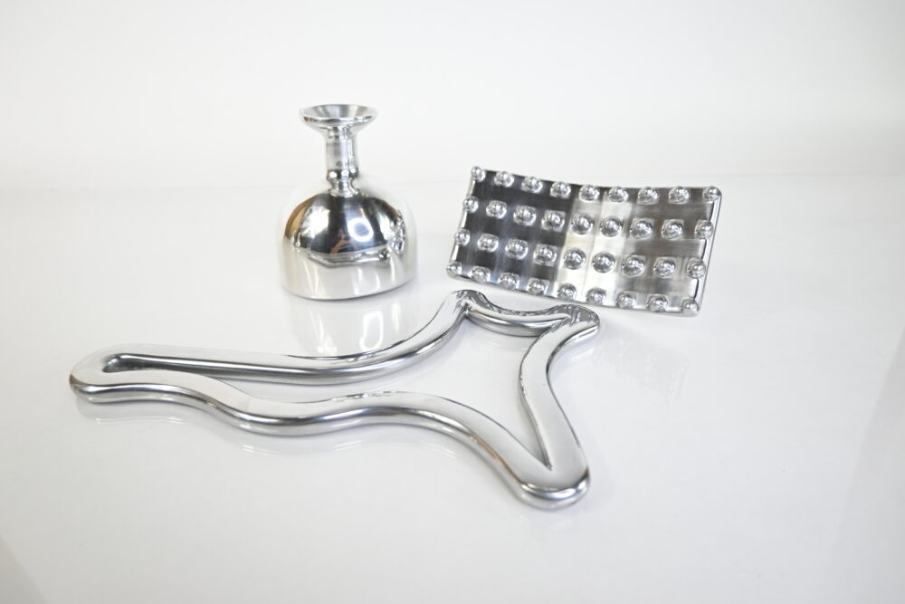 Set of polished aluminum Metal Therapy Tools for Ice Body Sculpting, including a metal body gua sha, Swedish cup, and mushroom tool, displayed on a reflective surface. Keywords: Metal Therapy Tools, Ice Body Sculpting, metal body gua sha, Metaloterapia corporal.