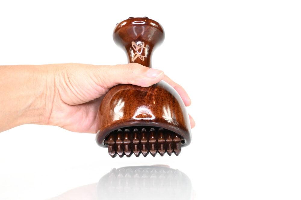 Hand holding lightweight maderoterapia cup with cob roller