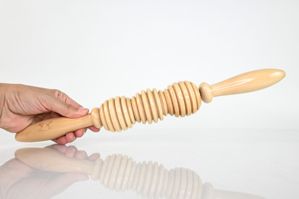 Hand holding a wooden deep tissue roller with rounded working sections